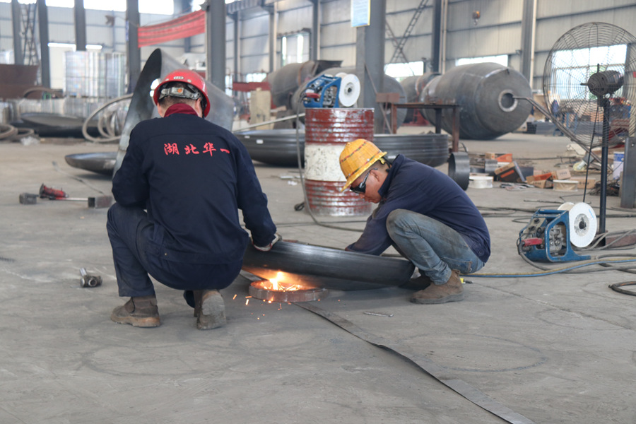 华一专汽搅拌车生产组的工人正在焊接搅拌罐前封头-加固及内衬钢板的焊接